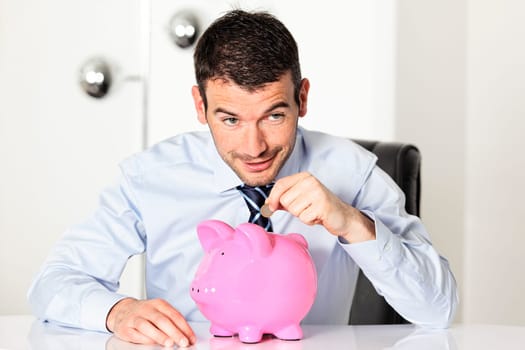 man with coin and pink piggy bank