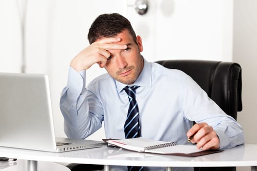 pensive man in office with computer and pen