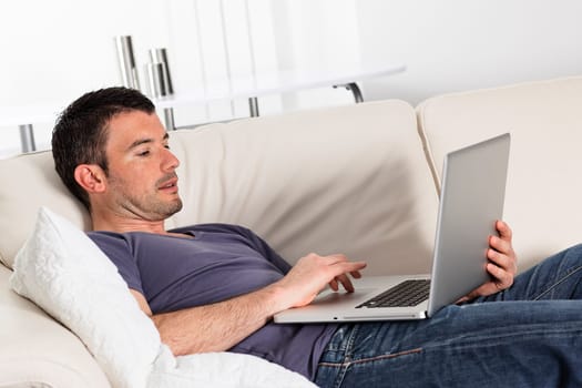 man using computer on sofa at home