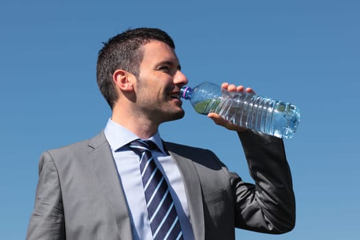 businessman drinking water with bottle and blue sky