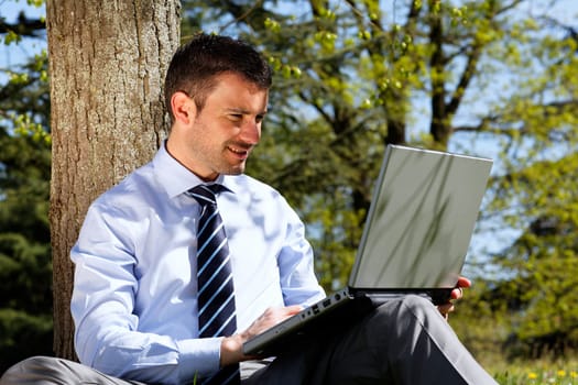 young businessman working on laptop in a park