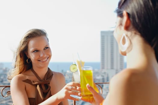 young caucasian female couple drinking cocktails and smiling on terrace in Havana, Cuba. Horizontal shape, waist up, copy space