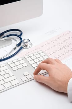 Doctor working with computer and electrocardiogram