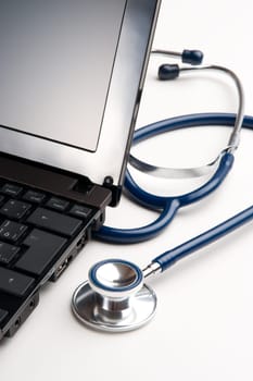 Part of stethoscope and laptop on white desk - general practitioner doctor workplace