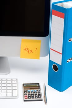 Tax concept - sticky notes with word tax, part of computer, keyboard, calculator, office folder and pen