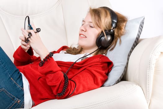 Young woman listening to music from cellphone lying on coach