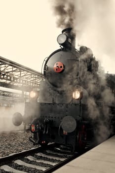 Steam locomotive at the railway station wrapped up in cloud - vintage retro tinting