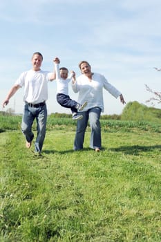 Young family with toddler playing angel flying