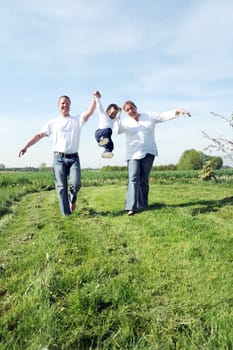 Young family with toddler running together across the field