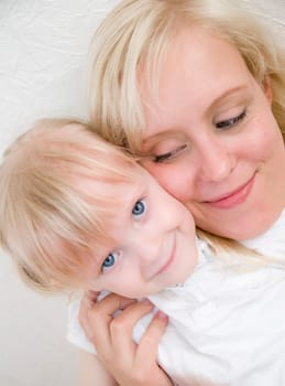 Head portrait of young blonde mother with blonde four-year-old daughter with faces touching sideways