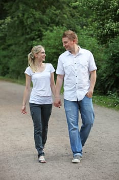 Young couple walking - both walking hand in hand and smiling.