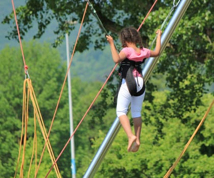 Young girl playing at a rope jumping game in nature background
