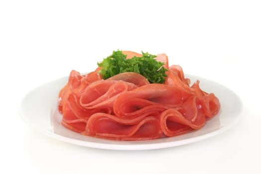 Salmon ham and a lettuce leaf on a white plate