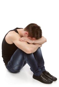 Young man thinking and hiding his face between his knees