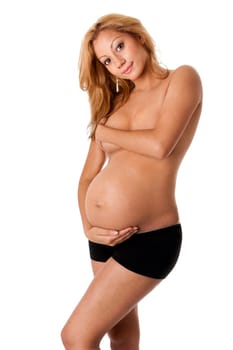 Beautiful new happy naked mother in late pregnancy wearing black panties, holding belly and covering breasts, isolated.
