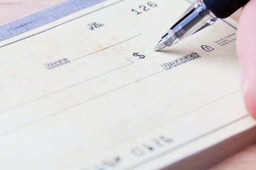 closeup of hand filling out the fields on a blank check