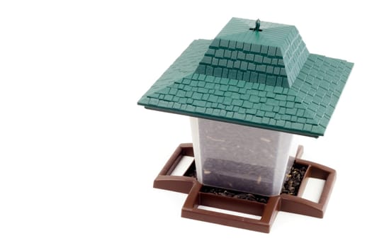 Plastic container with perches and roof to feed our feathered friends on white background.