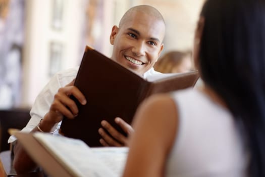 young adult hispanic couple dining out in restaurant and reading menu. Horizontal shape, waist up, focus on background