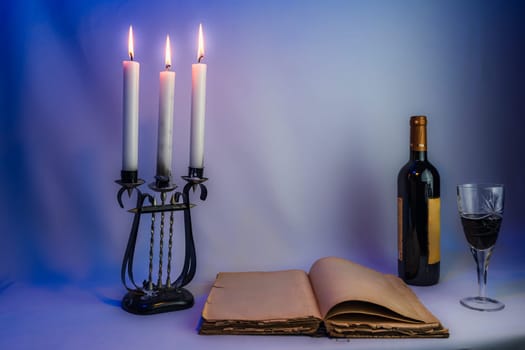 An open vintage book with aged pages, an antique candelabrum with burning candles, a wine bottle, and a filled glass, set in dim lighting, creating a mysterious and elegant atmosphere