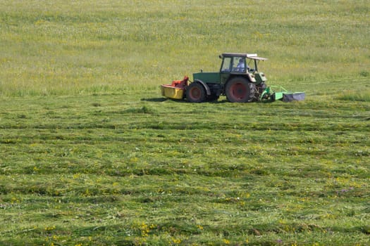 Farmer mowing the meadow in May