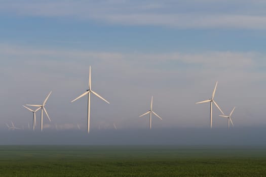 wind power turbines on a hill in fog