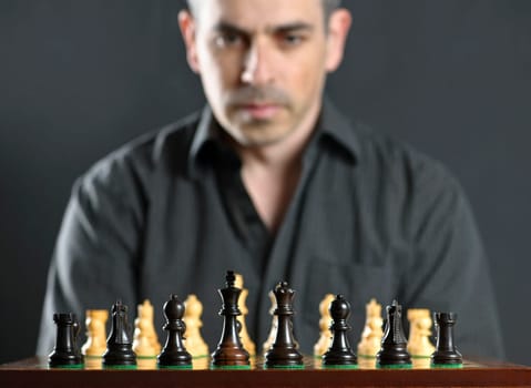 Man looking at wooden chess board thinking about first move