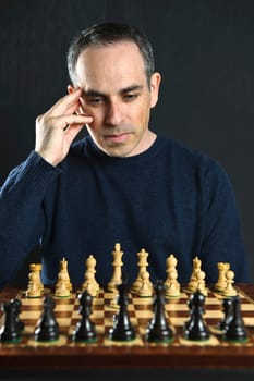 Man looking at wooden chess board thinking about first move