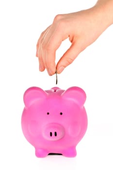 Hand putting coin into pink piggy bank slot