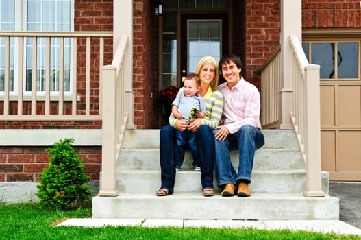 Young family sitting on front steps of house