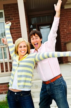 Young excited couple celebrating in front of home