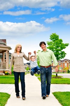 Young happy family playing with son on sidewalk