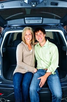 Happy young couple sitting at back of car