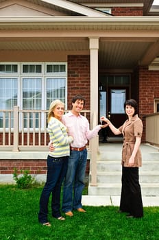 Happy couple getting keys to new house from real estate agent