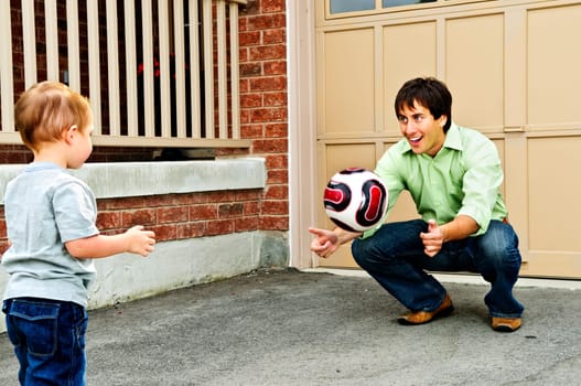 Father teaching son to play soccer on driveway