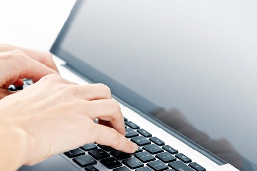 Hands typing on laptop computer keyboard close up
