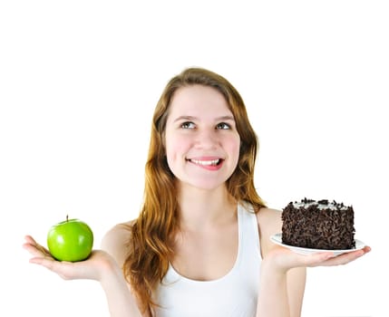 Tempted young woman holding apple and chocolate cake making a choice