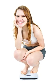 Healthy happy young woman crouching on bathroom scale isolated on white