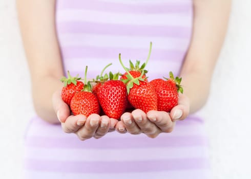 Girl hold fresh strawberries. Shallow DOF, focus on strawberries.