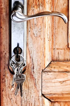 Set of keys in lock of old wooden door