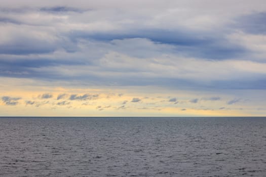 Distant horizon between cloud layer and calm seas at sunrise. High quality photo