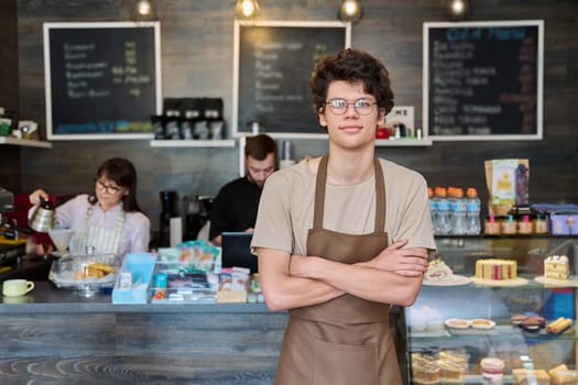 Coffee shop workers, a young guy in an apron in focus. Small business cafe cafeteria coffee house, job, work, staff people concept