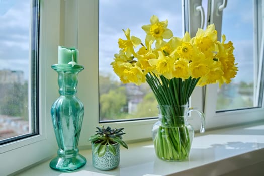 Bouquet of yellow daffodils in a transparent glass vase on the windowsill
