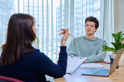 Guy student 18, 19 years old at therapy meeting with psychologist, social worker, mentor in college office. Social life, mental health, psychology, youth concept