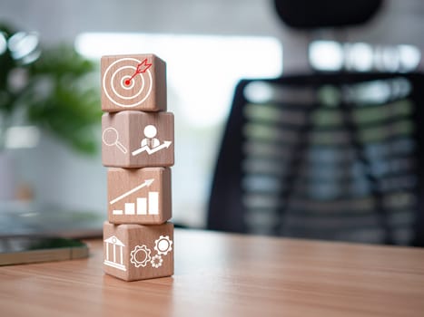 Wooden blocks and business icons on table wood represent the concept of business strategy and setting business goals.