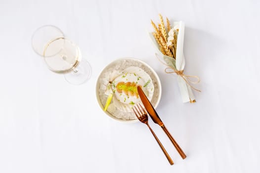 Scallop in sauce with flying fish caviar on a shell on ice in a restaurant. High quality photo