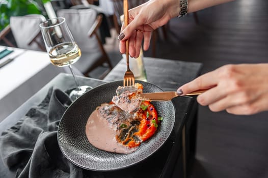 Sea bass or dorado fillet with sweet potato puree and flying fish roe sauce on a black plate in a restaurant