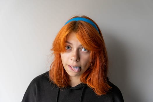 funny teen girl with red hair shows blue tongue. The girl is fooling around.