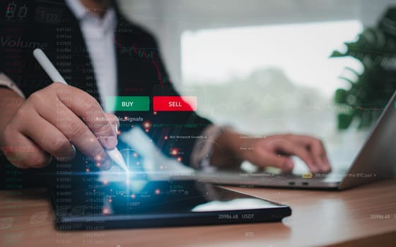 Businesswoman or trader is using a stylus pen pointing at a tablet showing trading and investing in the stock market.