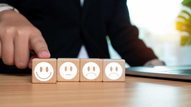 Businessman pointing fingers at smiley face and sad face on wooden block for positive thinking selection concept. Concepts of mental health and emotional state.