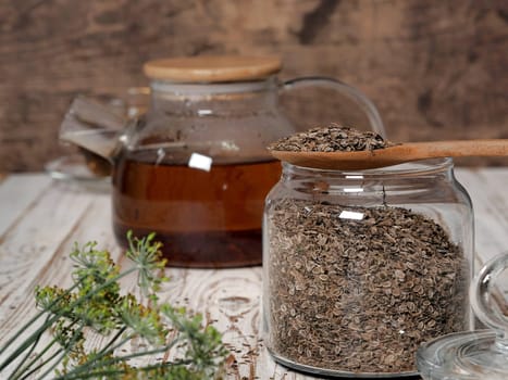 The concept of the usefulness of dill. Medicinal tea using dried dill seeds in a cup and teapot on a natural wooden table